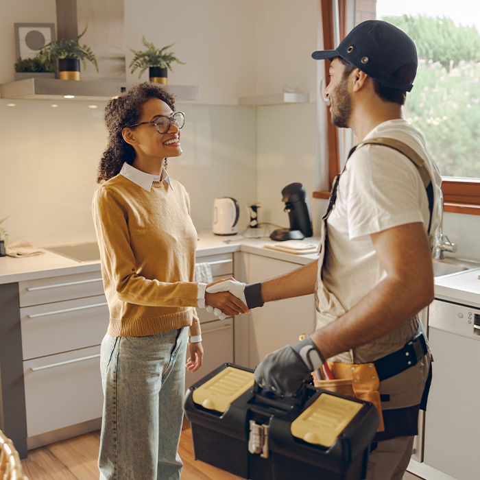 Professional repairman in uniform shaking hands with woman