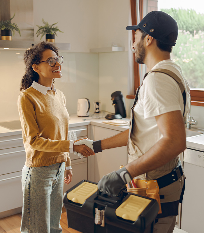 Professional repairman in uniform shaking hands with woman