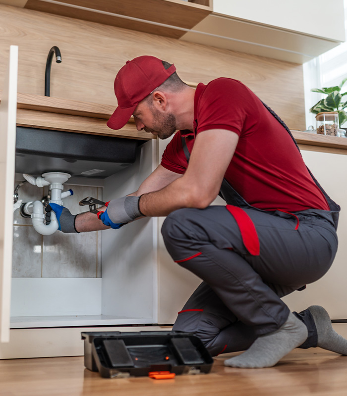 Plumber working on kitchen sink water pipes